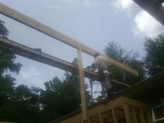 Carpenter setting a ridge beam over a new addition frame — Ice Dam Removal by Roofing Brothers in Cement