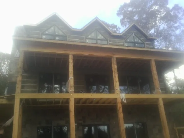 Dormers and porch framing on a large log home under construction — Roof Coating work by our crew in Cement
