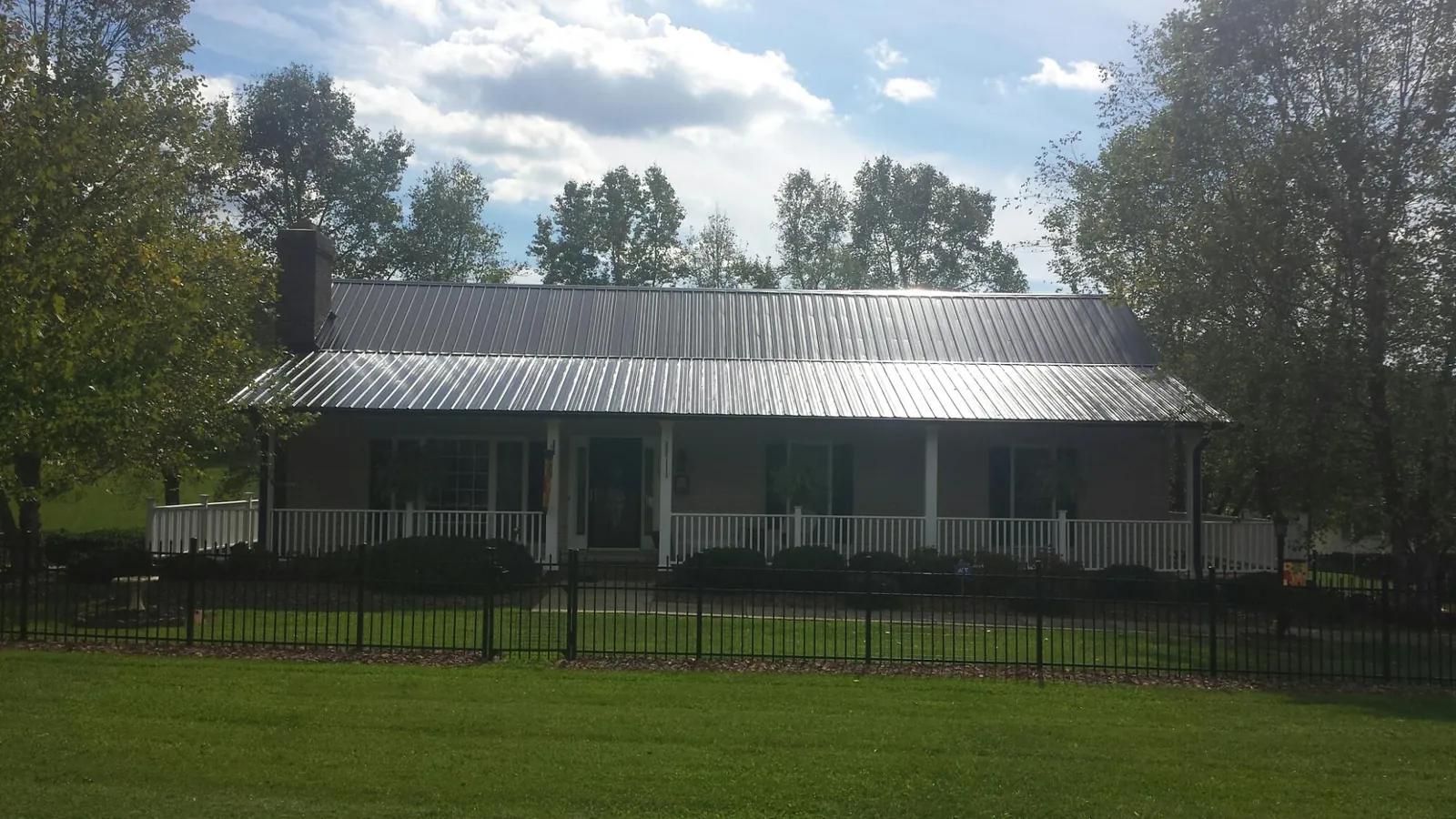 Gray metal roof on a brick ranch with a full width front porch — Gutter Guard Installation work by our crew in Cement